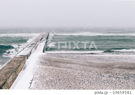 View of snow-covered pier and beach 33659581