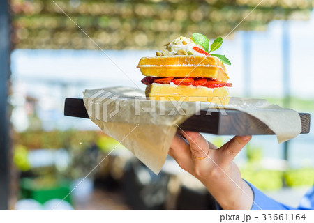 Close up hand holds Belgian waffles on tray 33661164