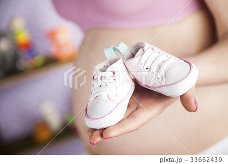 Pregnant woman holding a pair of tiny shoes Pregnant woman holding a pair of tiny shoes 33662439