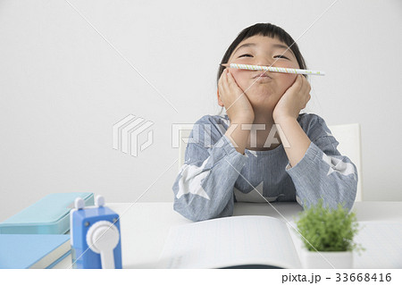 鉛筆を鼻の下に挟む 勉強シーン 小学生 考えるの写真素材