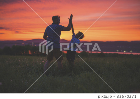silhouette of father and son at sunset 33670271