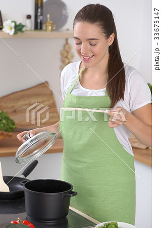 Young caucasian woman in a green apron cooking in 33673147