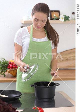 Young caucasian woman in a green apron cooking in 33673148