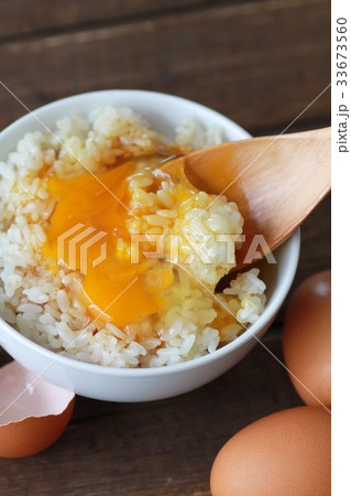 醤油をかけて黄身を崩した卵かけご飯と茶色の生卵 33673560