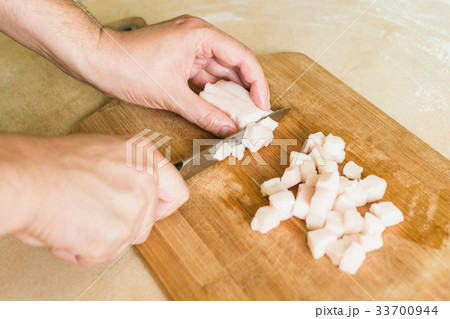 a man cuts raw pork fat into pieces 33700944