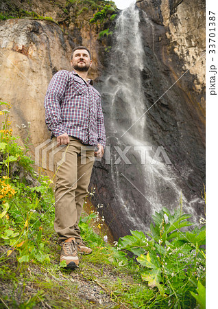 A bearded hipster in a plaid shirt stands against A bearded hipster in a plaid shirt stands against 33701387