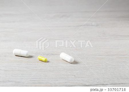 Three white and yellow medicine capsules 33701718