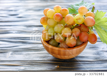 Bunch of pink grapes in a wooden bowl. 33702881