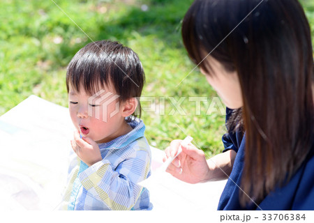 楽しいピクニックのランチ からあげを食べさせてもらう子ども ７の写真素材