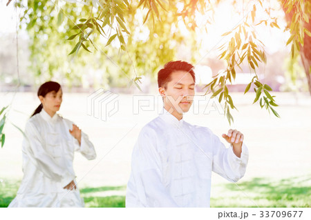 People practicing thai chi in park People practicing thai chi in park 33709677