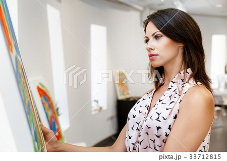 Young caucasian woman standing in art gallery front of paintings 33712815