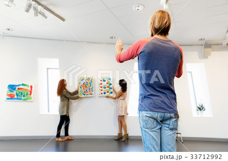 Young artists in gallery hanging painting on walls 33712992