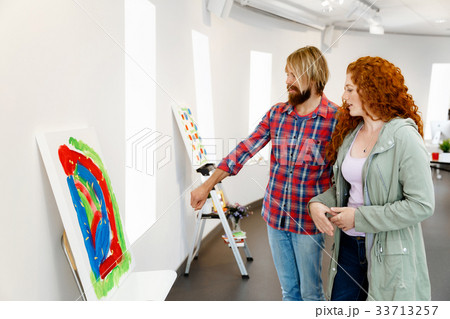 Young caucasian couple standing in a gallery and contemplating artwork 33713257