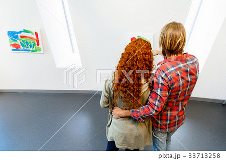 Young caucasian couple standing in a gallery and contemplating artwork 33713258