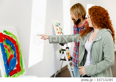 Young caucasian couple standing in a gallery and contemplating artwork Young caucasian couple standing in a gallery and contemplating artwork 33713285