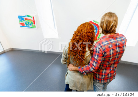 Young caucasian couple standing in a gallery and contemplating artwork Young caucasian couple standing in a gallery and contemplating artwork 33713304