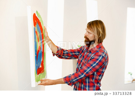 Young male artist standing with a picture Young male artist standing with a picture 33713328