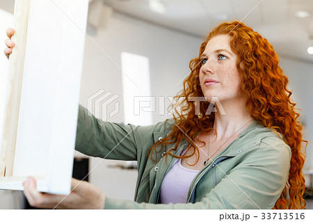 Young caucasian woman standing in art gallery front of paintings Young caucasian woman standing in art gallery front of paintings 33713516