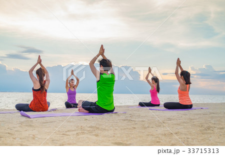 Yoga class at sea beach ,Group of people doing Yoga class at sea beach ,Group of people doing 33715313