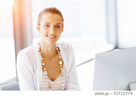 Attractive office worker sitting at desk Attractive office worker sitting at desk 33715774