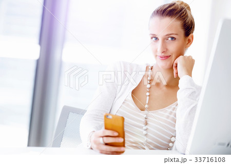 Attractive office worker sitting at desk 33716108