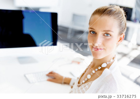 Attractive office worker sitting at desk Attractive office worker sitting at desk 33716275