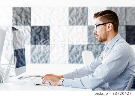 Male office worker sitting at desk 33720427