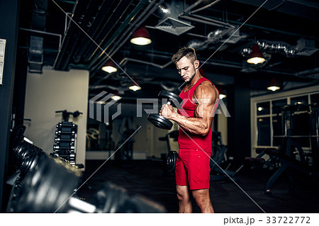 Bodybuilder lifting heavy black dumbbells at the 33722772