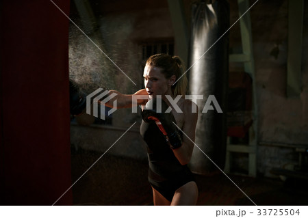 Boxing woman in black body hitting punching bag. 33725504