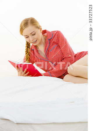 Woman relaxing in bed reading book Woman relaxing in bed reading book 33727523