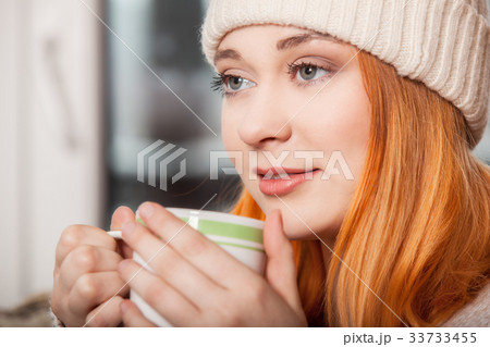Woman wearing warm clothing and drinking hot drink Woman wearing warm clothing and drinking hot drink 33733455