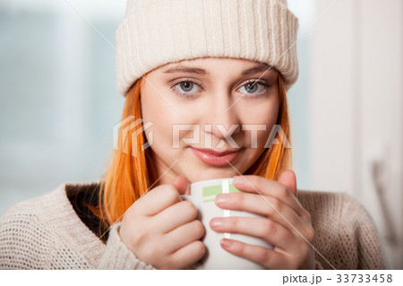 Woman wearing warm clothing and drinking hot drink 33733458