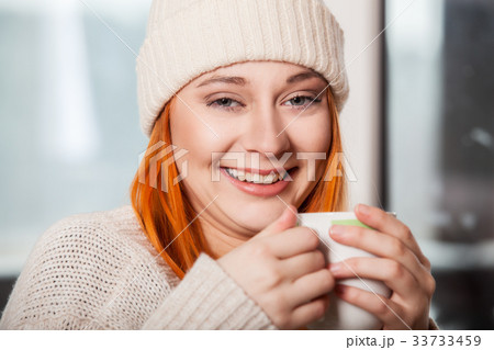 Woman wearing warm clothing and drinking hot drink 33733459