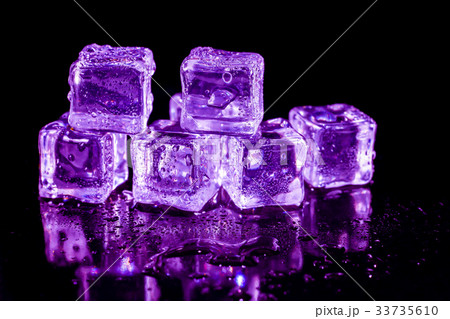 Purple ice cubes on a black table. 33735610