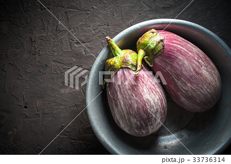 Colored eggplants in a metal bowl on a beige Colored eggplants in a metal bowl on a beige 33736314