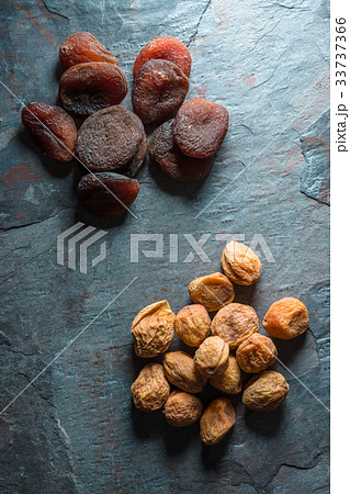 Yellow and brown dried apricots on a blue gray 33737366