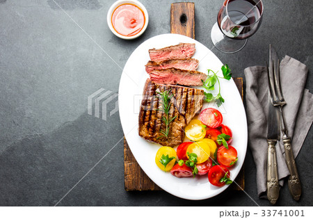 Sliced medium rare grilled beef steak served on 33741001