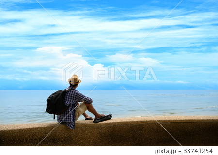 Traveler man with backpack standing at seaside Traveler man with backpack standing at seaside 33741254