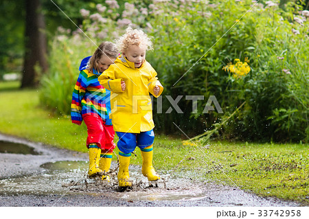 Kids play in rain and puddle in autumn Kids play in rain and puddle in autumn 33742958