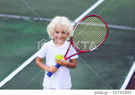 Child playing tennis on outdoor court Child playing tennis on outdoor court 33742995
