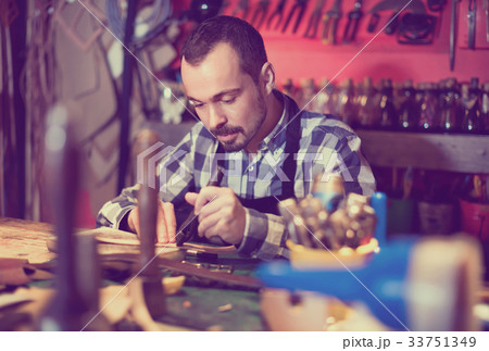 Male worker working on leather for belt in leather Male worker working on leather for belt in leather 33751349