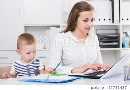 Mother is working on laptop while kid painting on papers 33751427