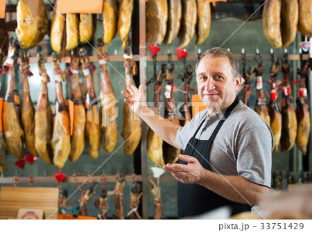 Smiling mature man seller working with tasty jamon 33751429