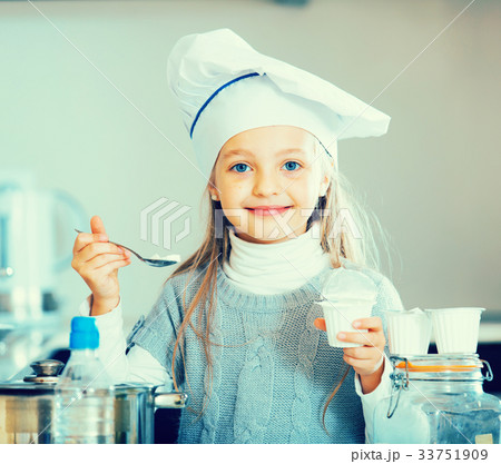 Little girl tasting fresh yoghurt in kitchen and smiling 33751909