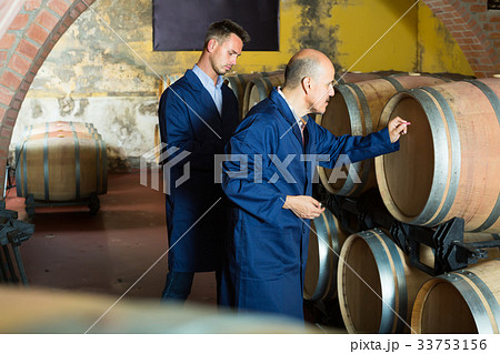 two busy men in uniforms taking notes in cellar with wine woods 33753156
