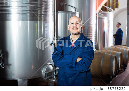 Portrait of cheerful mature man winery worker standing on wine factory 33753222