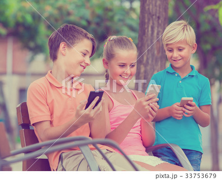 children are chatting in phones in the playground. 33753679