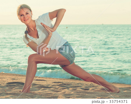 Smiling adult woman in white T-shirt is doing excercises on endurance Smiling adult woman in white T-shirt is doing excercises on endurance 33754371