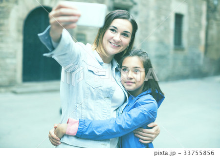 Smiling mother and daughter taking photo Smiling mother and daughter taking photo 33755856