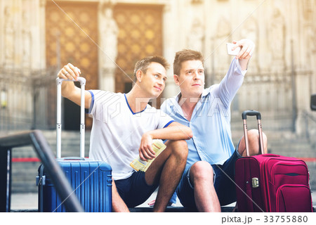 Two guys with luggage taking selfie in city at summer day 33755880